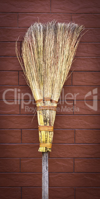 broom on a wooden handle stands near a brick wall