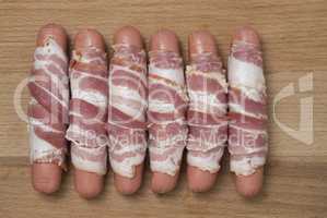 Raw sausages wrapped in smoked bacon ready to baked. Top view
