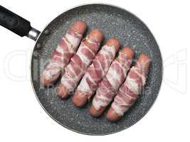 Preparation of raw sausages wrapped spirally in bacon on a fryin