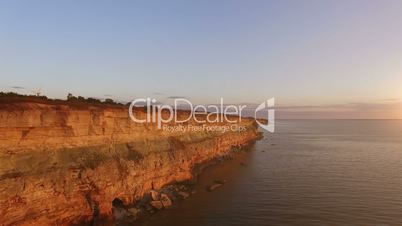 Aerial view of the precipice with terrible rocks by the sea at sunset