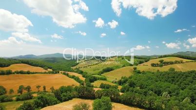 Aerial view of agricultural fields by summer cloudy day in Italy, Tuscany. In the background beautiful scenic nature