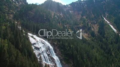 Aerial panoramic view of a waterfall on the pine forests and with sunlights in the mountains in Austria