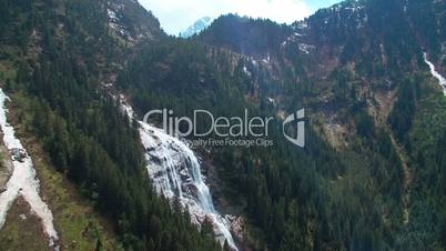 Aerial panoramic view of a waterfall on the pine forest and with sunlights in the mountains in Austria