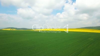 Aerial flight over the green field. Aerial view with background of blue sky and clouds. Tuscany, Italy