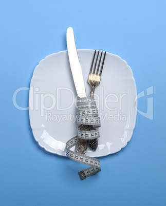 knife with a fork wrapped in a measuring tape with  ceramic plat
