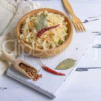 sauerkraut with carrots and green onions in a brown wooden bowl