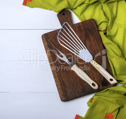 fork and scapula on a brown wooden board and green towel