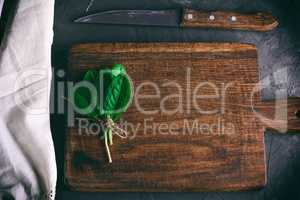 old brown wooden cutting board with handle and bunch with green