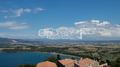 Time-lapse of clouds near the sea with yachts. In the background scenic beautiful mountains and fields. Italy, Tuscany, Piombino