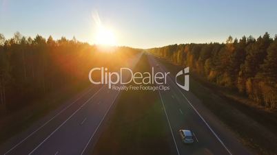 Aerial panoramic view of a highway with traffic along a mixed hardwoods and conifer forest at sunset