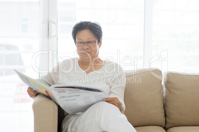 Asian senior woman reading newspaper
