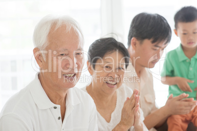 Happy Asian family clapping hands at home