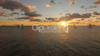 Aerial view of yachts with sails in the sea with a beautiful scenic sunset views. Yachts in the open sea