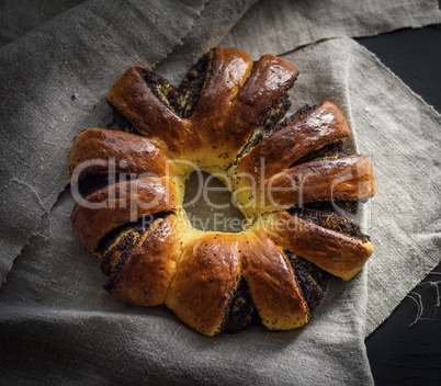 baked round pie with poppy seeds on a gray linen napkin