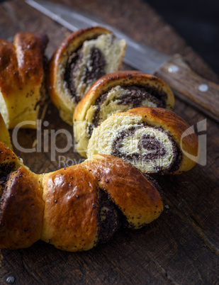 sliced roll with poppy seeds on a brown wooden board