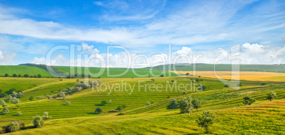 Green field and blue sky. Picturesque hills formed by an old riv
