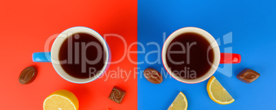 Red and blue cups with tea , lemon slices and chocolate candies