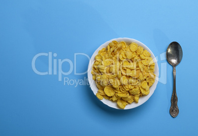 cornflakes in a white ceramic plate and an iron spoon