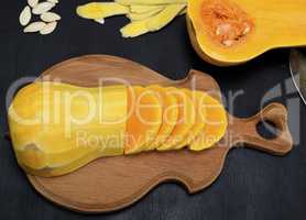 half of peeled pumpkin on wooden cutting board