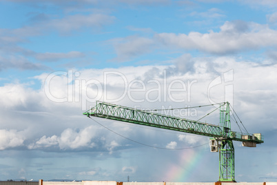 crane against blue sky with a rainbow after the rain