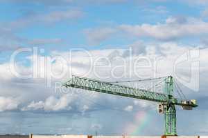 crane against blue sky with a rainbow after the rain