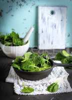 fresh green spinach leaves in a black round cast-iron frying pan