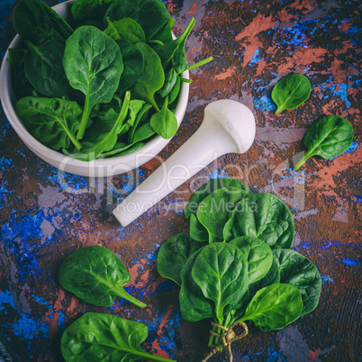 fresh green spinach leaves in a white ceramic mortar