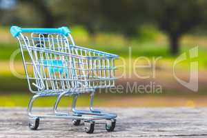 close up shopping cart on old wood table, green nature copy spac