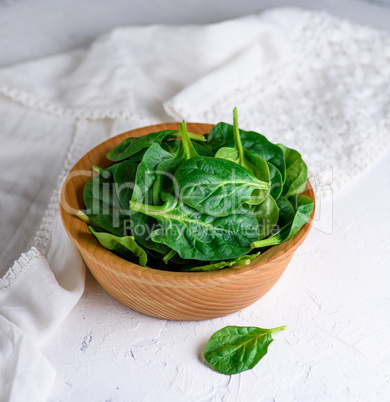 green spinach leaves in a brown wooden bowl