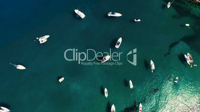 Aerial top view of sailing boat and yachts parked at the wild harbor near the coast in Spain, Catalonia