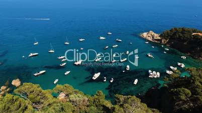 Aerial view of sailing boat and yachts parked at the wild harbor near the coast in Spain, Catalonia