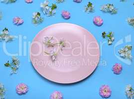 pink plate on a blue background in the midst of flowering buds