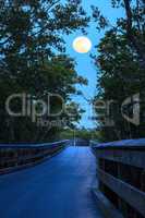 Moonrise over boardwalk over River leading to the ocean at Clam