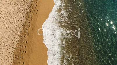 Aerial view of sea waves of reaching shore with yellow sandy. Spain, Catalonia