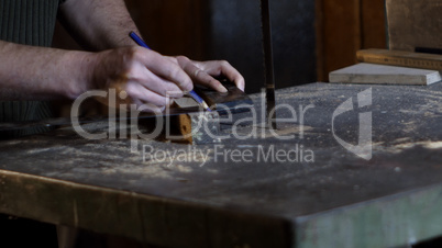 Carpenter measures and marks cutting line using a carpenter's ruler