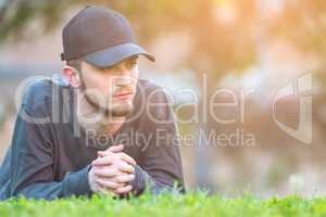 Close-up portrait of a young man lying down a green garden. Man