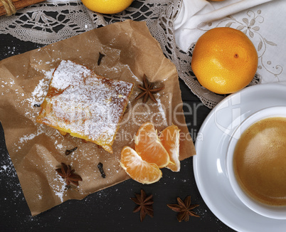 piece of mandarin pie with powdered sugar and white cup of coffe