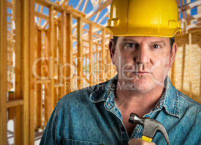Serious Contractor in Hard Hat Holding Hammer At Construction Si