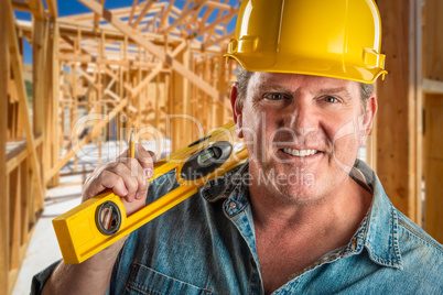 Smiling Contractor in Hard Hat Holding Level and Pencil At Const