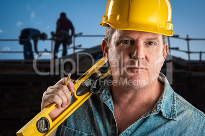 Serious Contractor in Hard Hat Holding Level and Pencil At Const