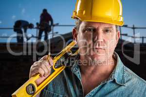 Serious Contractor in Hard Hat Holding Level and Pencil At Const