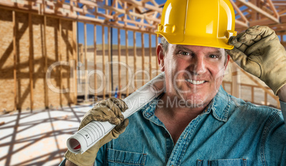 Smiling Contractor in Hard Hat Holding Floor Plans At Constructi