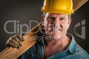 Smiling Contractor in Hard Hat Holding Plank of Wood With Dramat