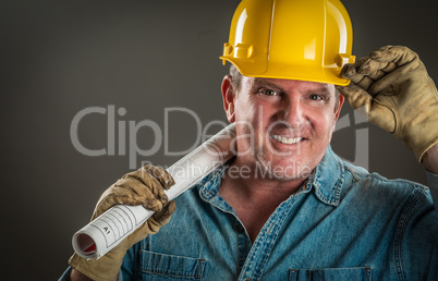 Smiling Contractor in Hard Hat Holding Floor Plans With Dramatic