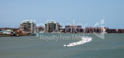 Skyline in the background as a Group of jet skies zip along the