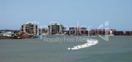 Skyline in the background as a Group of jet skies zip along the