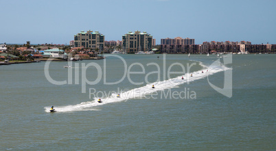 Skyline in the background as a Group of jet skies zip along the