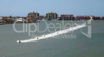 Skyline in the background as a Group of jet skies zip along the