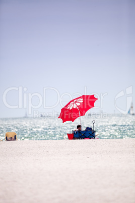 Blue sky over a red umbrella and white sand