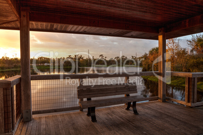 Sunset Wooden bench on a secluded, tranquil boardwalk along a ma